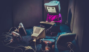 Noticias Curiosidades muestra a una persona con un monitor de computadora en la cabeza, rodeada de antiguas pantallas CRT, representando noticias curiosidades y eventos insólitos. Esta imagen es adecuada para artículos sobre noticias raras, sorprendentes y extrañas.