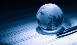 Globo terráqueo sobre una tabla de datos financieros con un bolígrafo de Noticias Economía Online.