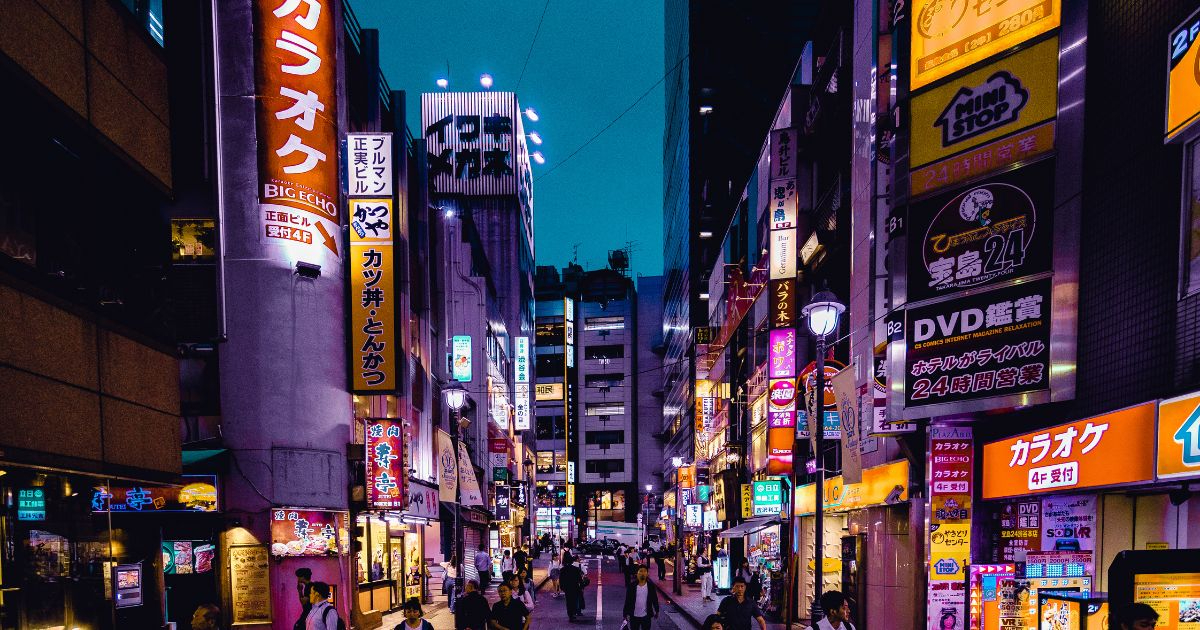 Calle nocturna en Tokio iluminada con coloridos letreros y anuncios, representando la mejor época para viajar a Tokio y explorar la cultura japonesa.
