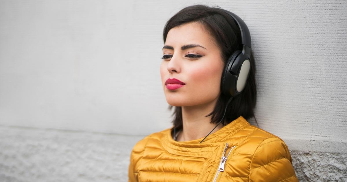 Mujer joven escuchando uno de los mejores podcasts, representando el disfrute y la inmersión que ofrecen los archivos de audio digital en el tiempo de escucha personal.