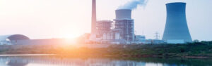 Empresas de uranio muestra una central nuclear junto a un cuerpo de agua, representando mercado de uranio y la producción de energía nuclear. Esta imagen es adecuada para artículos sobre empresas de uranio, centrales nucleares y la energía nuclear.
