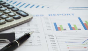 Noticias Mercado Financiero muestra un informe financiero con gráficos, una calculadora y un bolígrafo, representando noticias mercado financiero y el análisis de los mercados financieros globales. Esta imagen es adecuada para artículos sobre inversiones internacionales y mercados de valores.