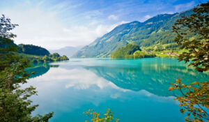 Lago sereno reflejando montañas y cielo, ilustrando la belleza y la importancia de la conservación en Noticias Naturaleza.