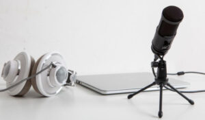 Noticias Podcast muestra un micrófono profesional, auriculares y una laptop sobre una mesa, representando noticias podcast y la producción de podcasts. Esta imagen es adecuada para artículos sobre tendencias y novedades en el mundo del podcasting.