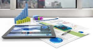 Escenario de oficina con gráficos tridimensionales, una calculadora, y una tableta digital abierta en una revista de economía financiera, representando la gestión de revistas financieras y finanzas personales.