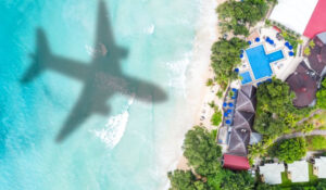 Sombra de un avión sobre una playa paradisíaca, representando Noticias Viajar.