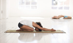 Mujer practicando yoga en meditación frente al mar, destacando en Noticias Yoga y sus beneficios.